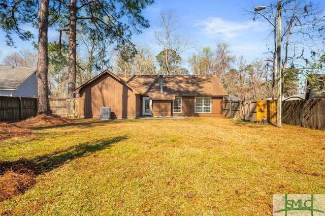 rear view of property with a lawn, central AC, a fenced backyard, and a gate