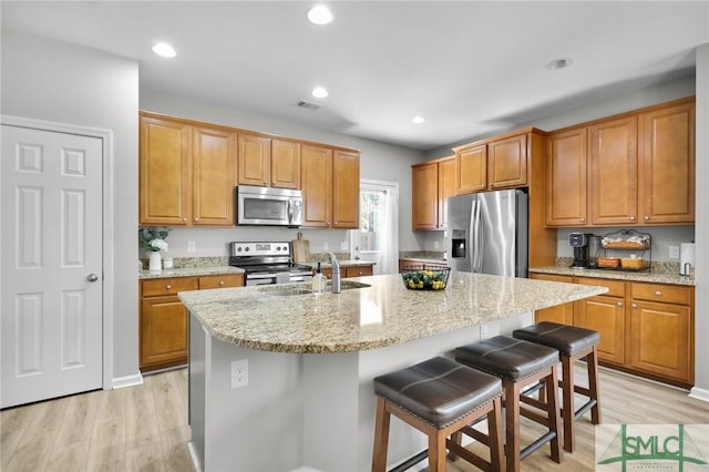 kitchen featuring light stone counters, visible vents, light wood-style flooring, and appliances with stainless steel finishes