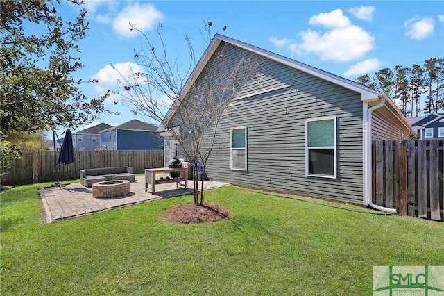 rear view of property with a yard, a patio, a fenced backyard, and an outdoor fire pit