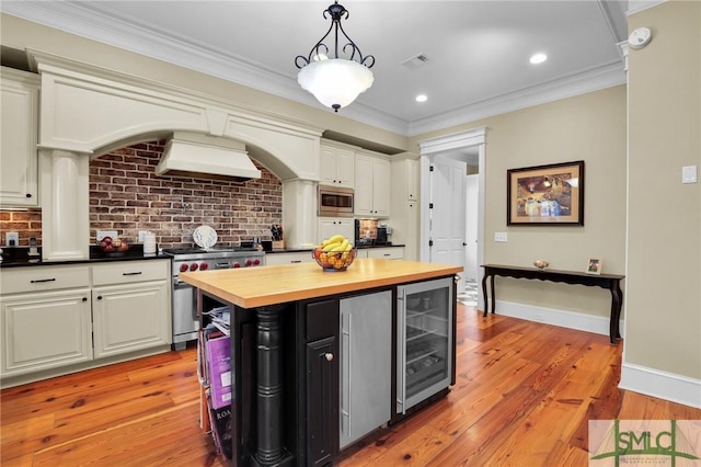 kitchen featuring beverage cooler, ornamental molding, custom range hood, appliances with stainless steel finishes, and wood counters