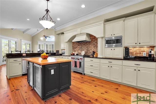 kitchen with premium range hood, a kitchen island, appliances with stainless steel finishes, white cabinets, and lofted ceiling