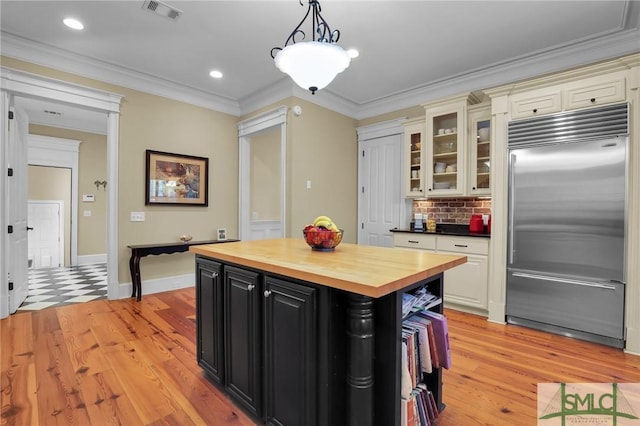 kitchen featuring visible vents, butcher block countertops, ornamental molding, dark cabinetry, and built in fridge