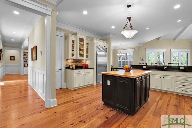 kitchen with white cabinetry, butcher block counters, built in refrigerator, and a sink