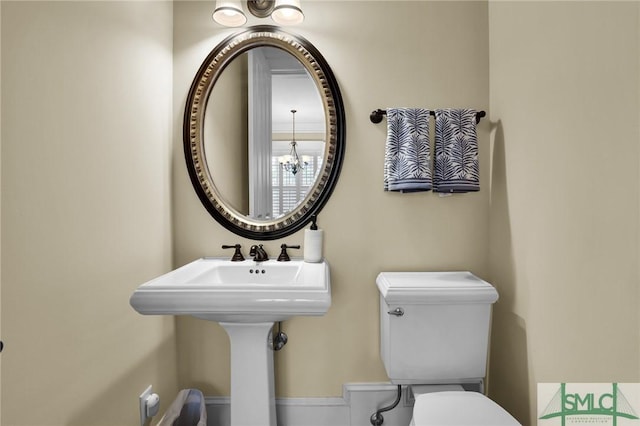 bathroom with toilet and an inviting chandelier