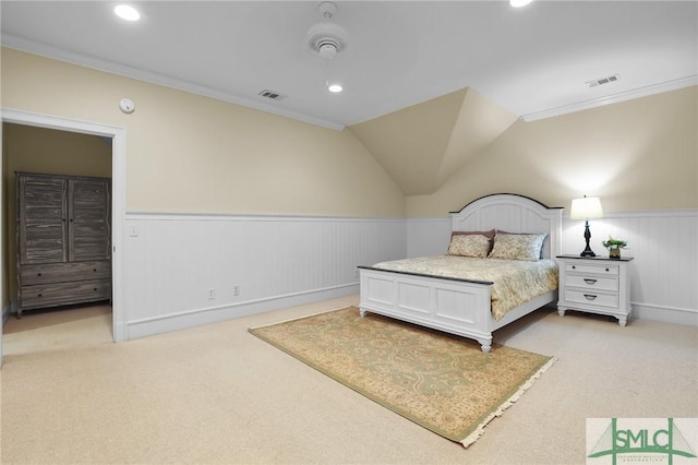 bedroom featuring visible vents, light carpet, and a wainscoted wall