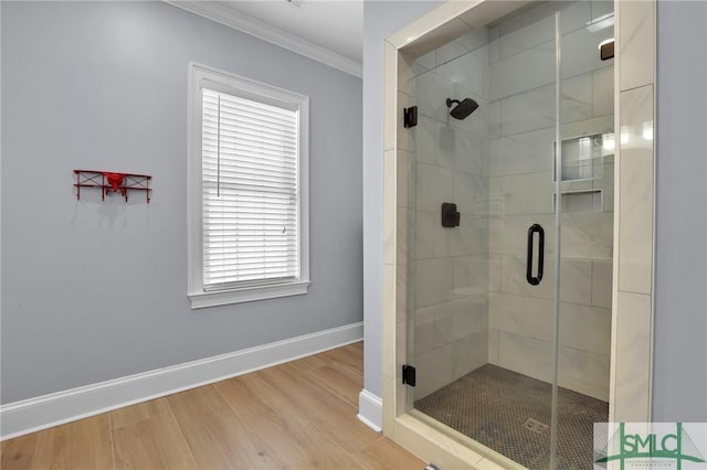 bathroom featuring baseboards, a shower stall, wood finished floors, and crown molding