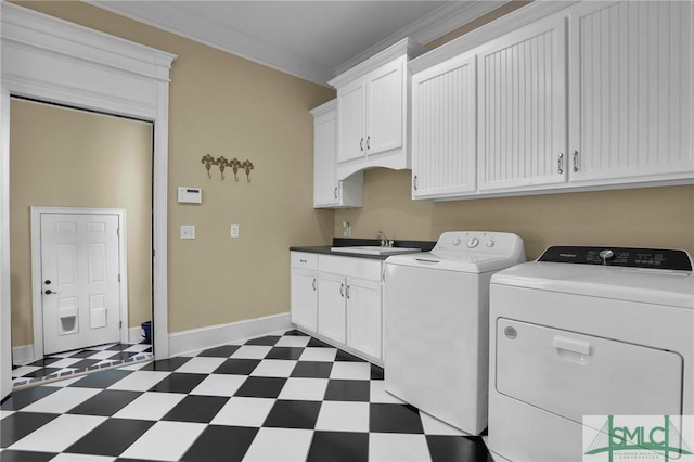 laundry room featuring dark floors, cabinet space, a sink, ornamental molding, and washing machine and dryer