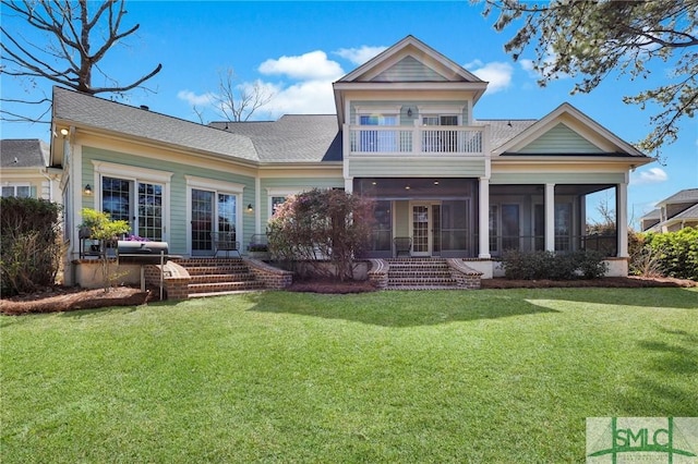 back of house featuring a balcony, a shingled roof, a lawn, and a sunroom