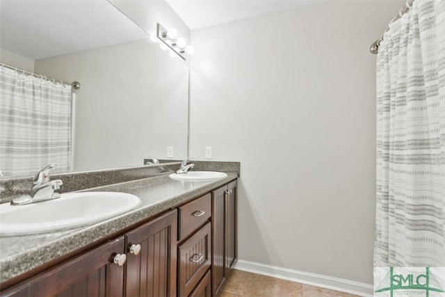 full bath with a sink, baseboards, double vanity, and tile patterned flooring