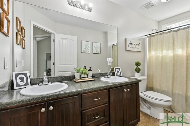 full bath with double vanity, visible vents, toilet, and a sink