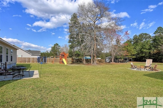 view of yard featuring a patio, a playground, a fire pit, and fence