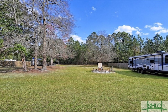 view of yard with fence and an outdoor fire pit