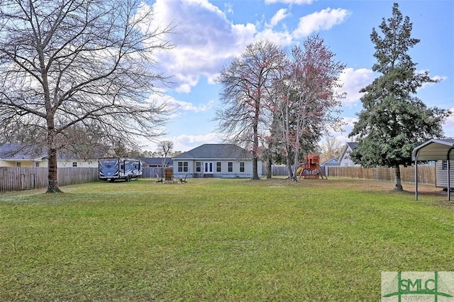 view of yard featuring a detached carport, a playground, and fence