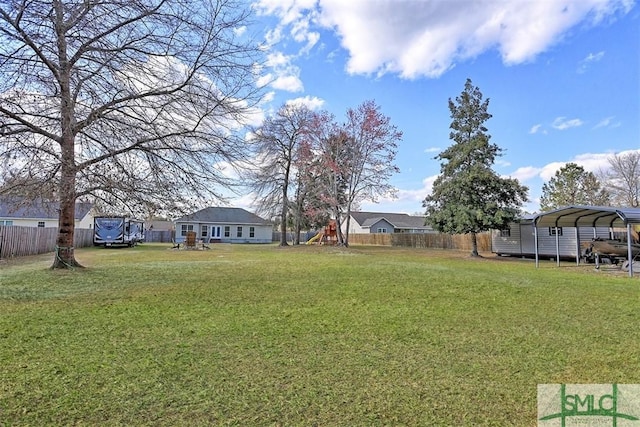 view of yard featuring fence, a detached carport, and a playground