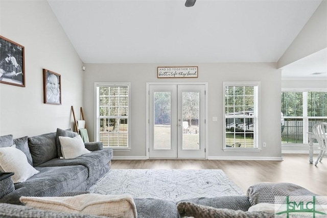 living area with a wealth of natural light, wood finished floors, and vaulted ceiling