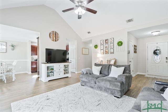 living room featuring wood finished floors, baseboards, visible vents, high vaulted ceiling, and ceiling fan