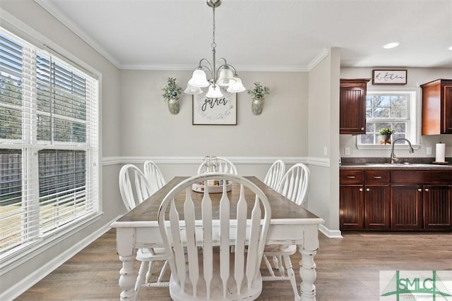 dining room with baseboards, a chandelier, ornamental molding, and light wood finished floors