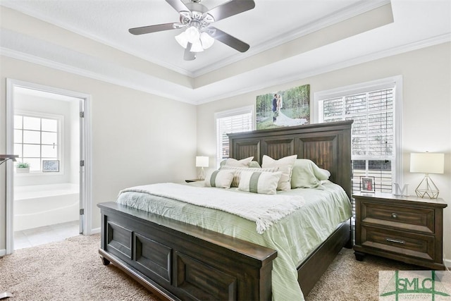 bedroom featuring ornamental molding, a tray ceiling, ensuite bath, carpet flooring, and baseboards