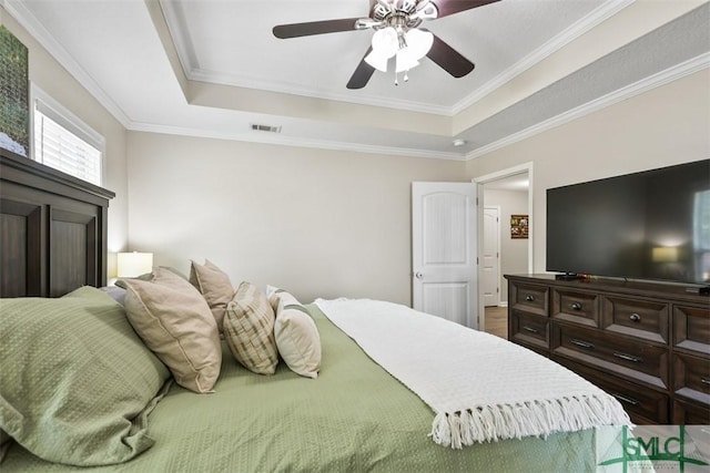 bedroom with visible vents, ceiling fan, crown molding, and a tray ceiling