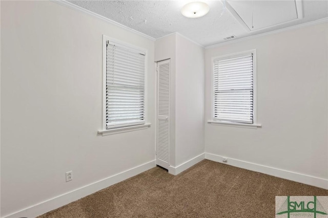 unfurnished room with baseboards, visible vents, attic access, a textured ceiling, and dark carpet