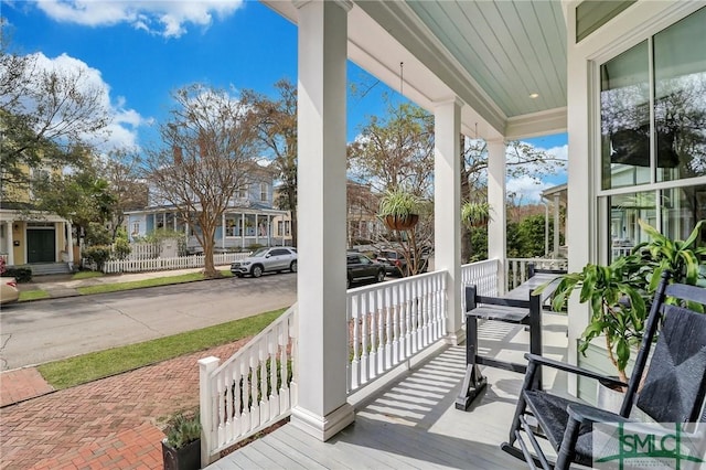 wooden terrace featuring a residential view and covered porch