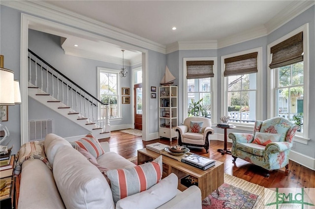 living room featuring stairs, crown molding, wood finished floors, and visible vents