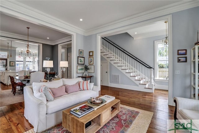 living room featuring visible vents, stairway, ornamental molding, hardwood / wood-style floors, and a notable chandelier