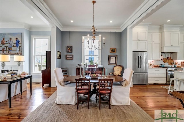 dining space featuring an inviting chandelier, wood finished floors, and crown molding