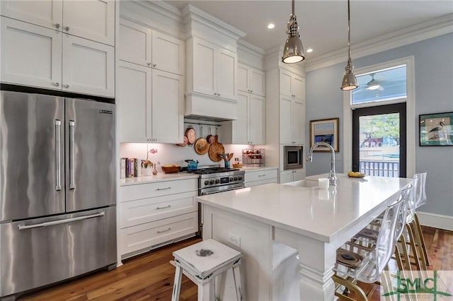 kitchen with a sink, high quality appliances, ornamental molding, and light countertops