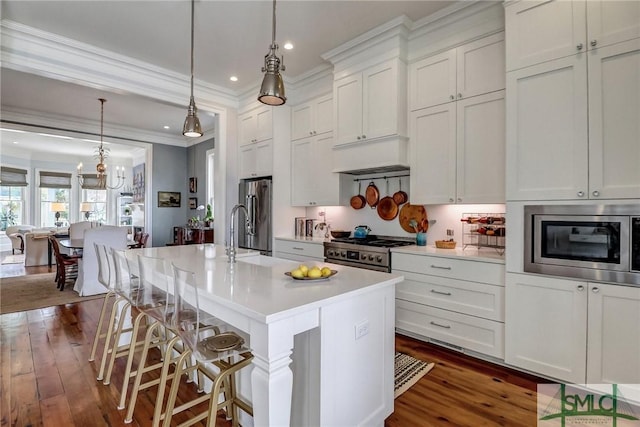 kitchen featuring a breakfast bar area, an island with sink, light countertops, white cabinets, and appliances with stainless steel finishes