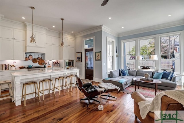 living room featuring recessed lighting, baseboards, wood-type flooring, and ornamental molding