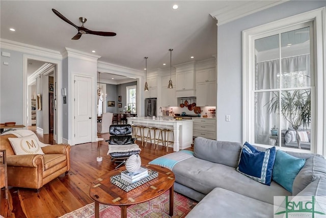 living area with wood finished floors, recessed lighting, crown molding, baseboards, and ceiling fan