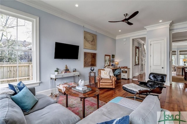 living room featuring crown molding, wood finished floors, baseboards, and ceiling fan