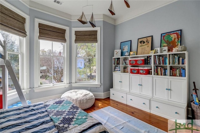 bedroom with crown molding, multiple windows, and wood finished floors