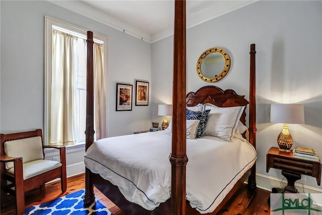 bedroom with wood finished floors, baseboards, and ornamental molding