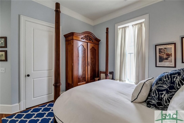 bedroom with crown molding, wood finished floors, and baseboards