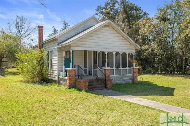 bungalow featuring cooling unit, a porch, a chimney, and a front yard