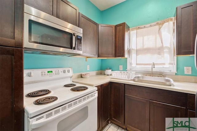 kitchen with a sink, stainless steel microwave, dark brown cabinetry, and white range with electric stovetop