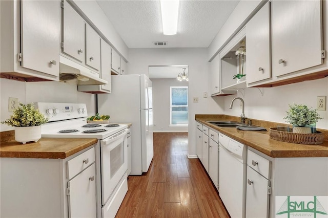 kitchen with visible vents, under cabinet range hood, wood finished floors, white appliances, and a sink