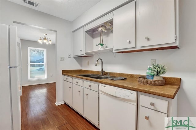 kitchen featuring visible vents, dark wood-type flooring, white cabinets, white appliances, and a sink