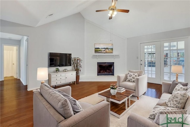 living area featuring a large fireplace, baseboards, lofted ceiling, wood finished floors, and a ceiling fan