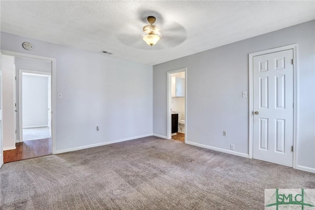 interior space featuring visible vents, a textured ceiling, ensuite bath, carpet flooring, and baseboards