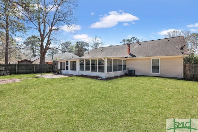 rear view of house with roof with shingles, a fenced backyard, a sunroom, central air condition unit, and a lawn