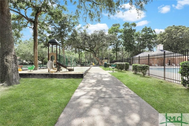 view of community with a swimming pool, a lawn, playground community, and fence