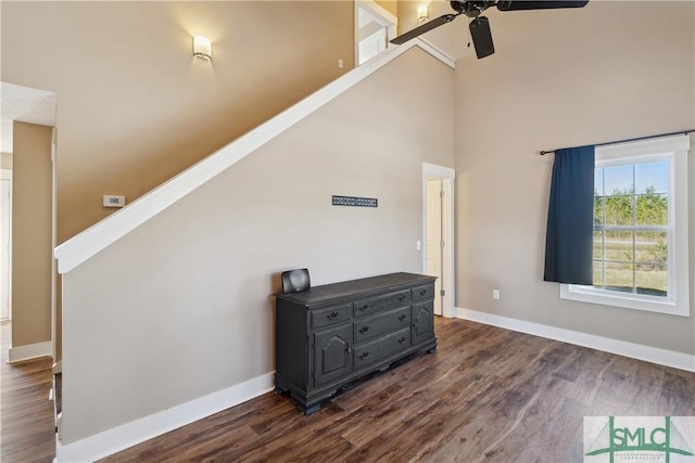 interior space with baseboards, a high ceiling, dark wood-style flooring, ceiling fan, and stairs