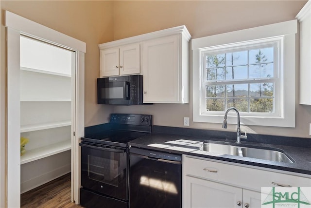 kitchen featuring a sink, dark countertops, black appliances, and white cabinetry