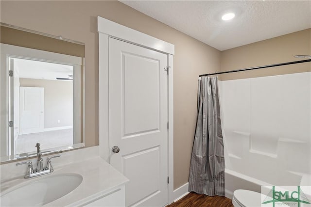 bathroom with toilet, vanity, shower / bath combo, wood finished floors, and a textured ceiling