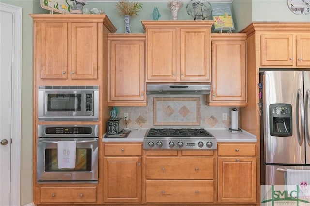 kitchen featuring under cabinet range hood, stainless steel appliances, light countertops, and tasteful backsplash