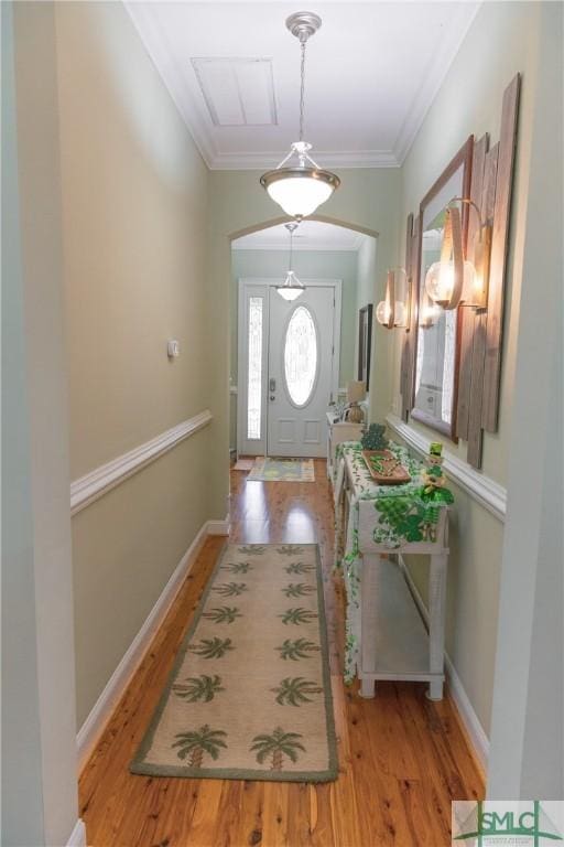 foyer entrance with arched walkways, wood finished floors, baseboards, and ornamental molding