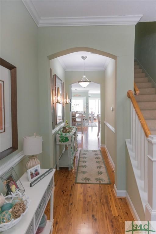 corridor with baseboards, light wood-style flooring, stairs, and crown molding